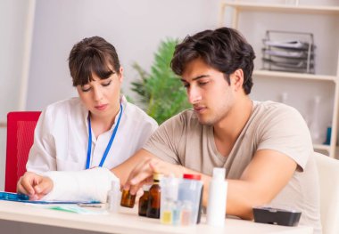 Kolu bandajlı genç adam kadın doktor travmatologunu ziyaret ediyor.