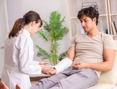Kolu bandajlı genç adam kadın doktor travmatologunu ziyaret ediyor.