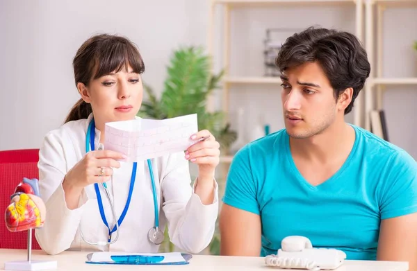 Hombre joven visitando al médico cardiólogo femenino — Foto de Stock