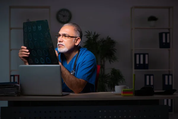 Aged male doctor in the hospital at night — Stock Photo, Image