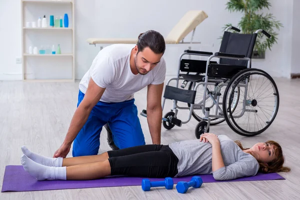 Donna infortunata alla gamba che fa esercizi sportivi con allenatore personale — Foto Stock