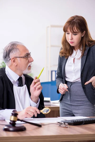 Oude mannelijke rechter en zijn jonge secretaresse op kantoor — Stockfoto