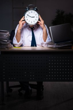 İş yerinde geç saatlere kadar çalışan yaşlı bir erkek işçi.