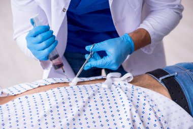 Yaşlı adam genç erkek stajyer doktoru ziyaret ediyor.