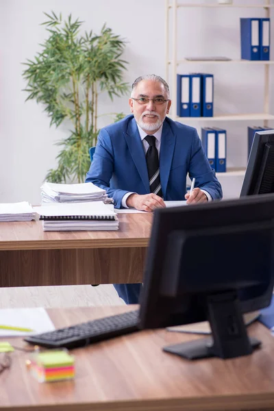 Velho empregado masculino e excesso de trabalho no escritório — Fotografia de Stock