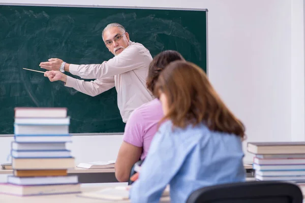 Old chemist teacher and two students in the classroom