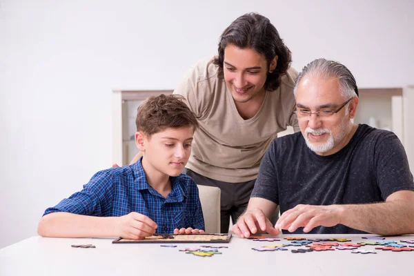 Tre generazioni di famiglia che giocano puzzle game — Foto Stock