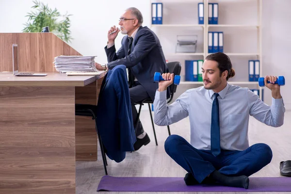 Two employees doing physical exercises at workplace — Stock Photo, Image