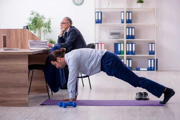İki çalışan işyerinde fiziksel egzersiz yapıyor.
