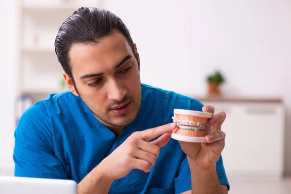 Jonge mannelijke tandarts werkzaam in de kliniek — Stockfoto