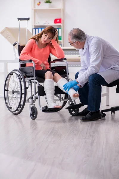 Młoda noga ranna kobieta odwiedza starego lekarza traumatologa — Zdjęcie stockowe