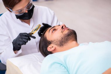 Genç adam saç nakli dolandırıcılığında kadın güzellik uzmanını ziyaret ediyor.