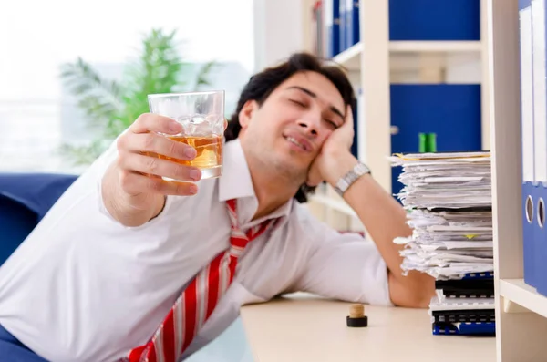 Молодой бизнесмен пьет в офисе — стоковое фото