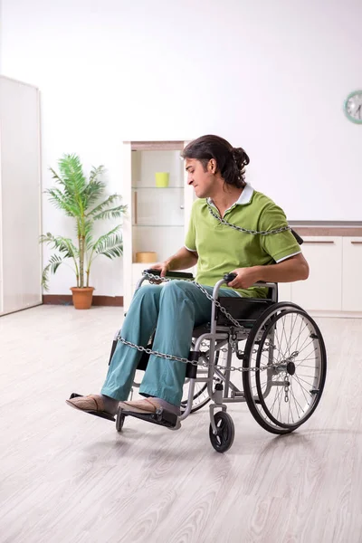 Giovane maschio invalido in sedia a rotelle che soffre a casa — Foto Stock
