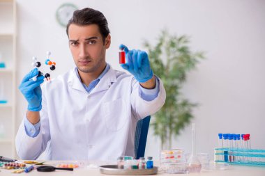 Uyuşturucu sentezi konseptinde genç erkek laboratuvar asistanı