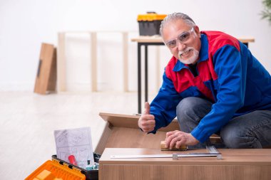 Yaşlı erkek marangoz içeride çalışıyor.