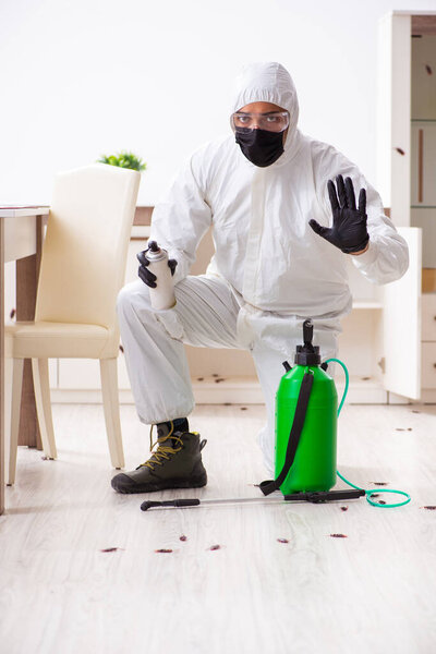 Young male contractor doing pest control at home