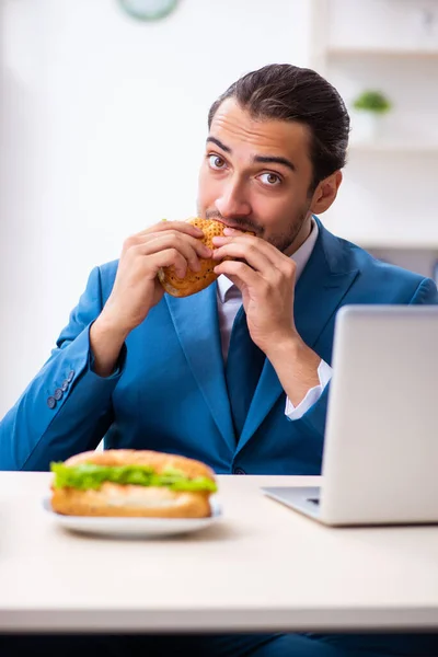 Joven empleado masculino desayunando en el lugar de trabajo — Foto de Stock