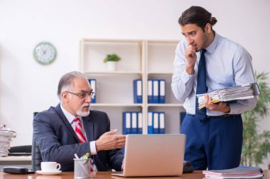 Eski patron ve genç erkek çalışan ofiste.