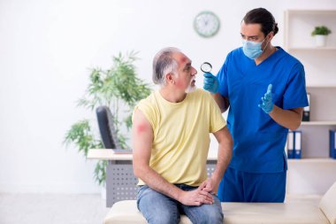 Yaralı yaşlı adam genç erkek doktor travmatoloğu ziyaret ediyor.