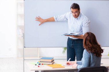 Genç bayan öğrenci ve erkek öğretmen sınıfta.