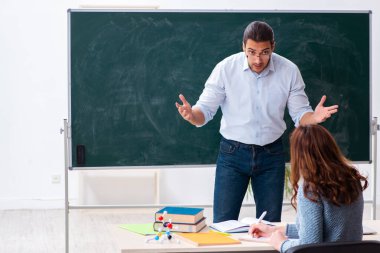 Genç bayan öğrenci ve erkek öğretmen sınıfta.