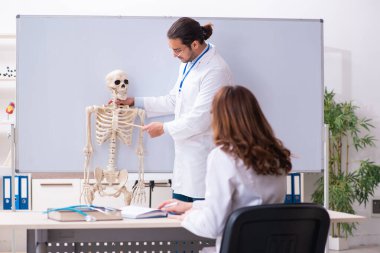 Genç erkek öğretmen doktor, iskelet ve kız öğrenci.