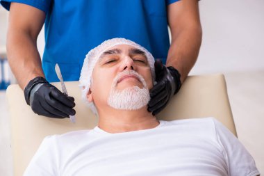 Yaşlı adam estetik ameliyat için erkek doktoru ziyaret ediyor.