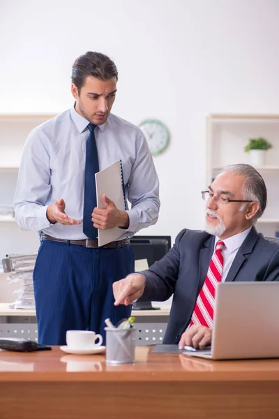 Oude baas en jonge mannelijke werknemer in het kantoor — Stockfoto