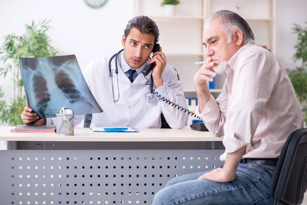 Jonge mannelijke arts en oude patiënt in antismoking concept — Stockfoto