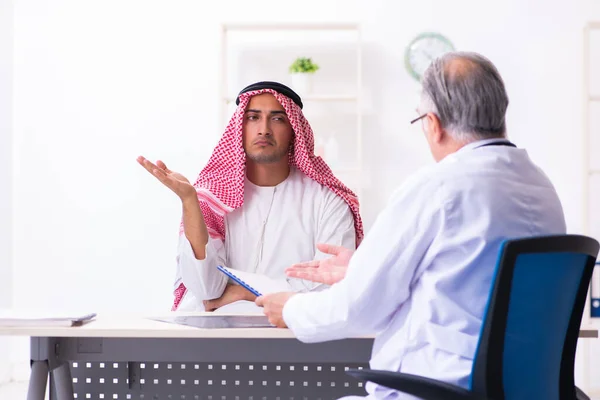 Young male arab visiting experienced male doctor — Stock Fotó