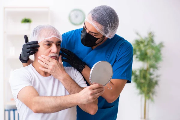 Старик посещает врача-мужчину для пластической хирургии — стоковое фото