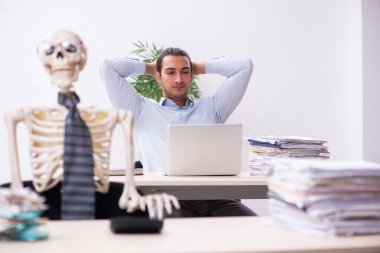 Genç erkek çalışan ve iskelet ofiste.