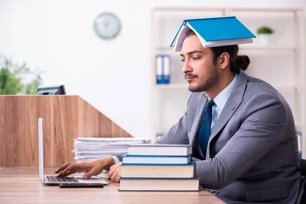 Jonge mannelijke zakenman die boeken leest op het werk — Stockfoto