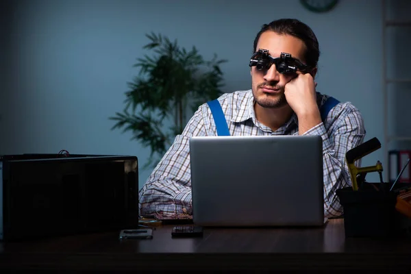 Joven técnico masculino reparando el ordenador en el taller por la noche — Foto de Stock