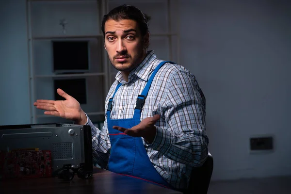 Jonge mannelijke technicus repareert computer in de werkplaats 's nachts — Stockfoto