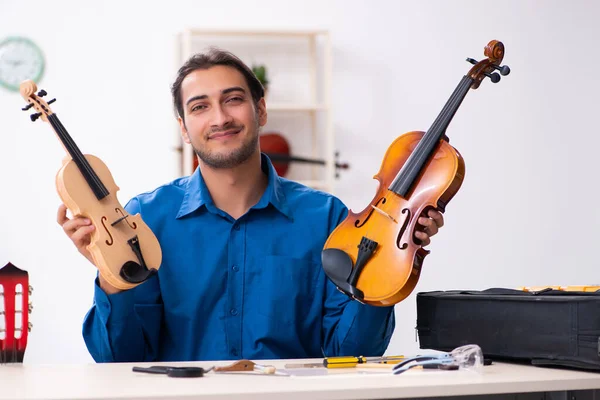 Jovem reparador do sexo masculino reparando violino — Fotografia de Stock