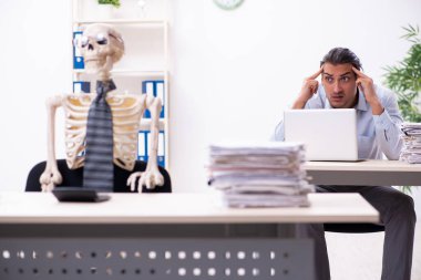 Genç erkek çalışan ve iskelet ofiste.