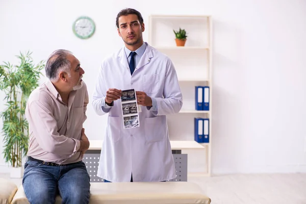 Vieux patient visitant jeune médecin masculin — Photo