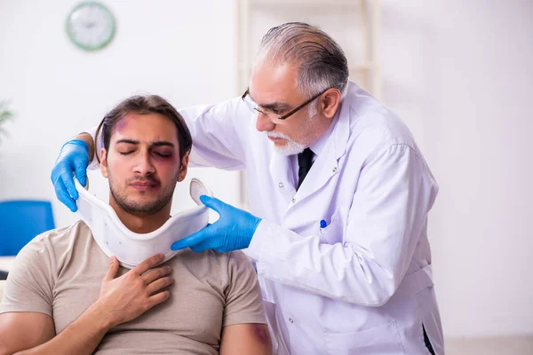 Ung ansikte skadad man besöker erfaren manlig läkare traumat — Stockfoto