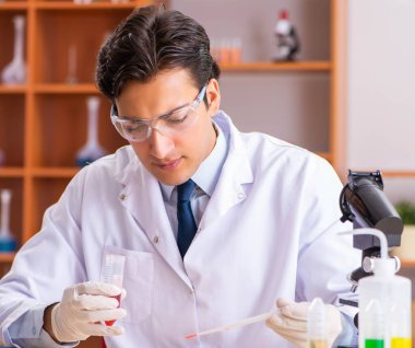 Genç yakışıklı biyokimyacı laboratuvarda çalışıyor.