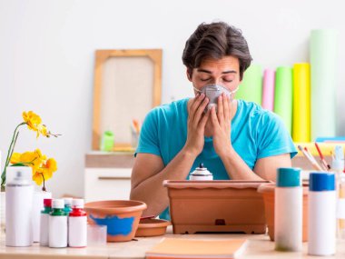 Sınıfta çömlek dekorasyonu yapan genç bir adam.