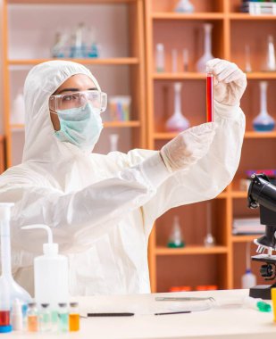 Laboratuvarda çalışan koruyucu elbise giyen genç bir biyokimyacı.