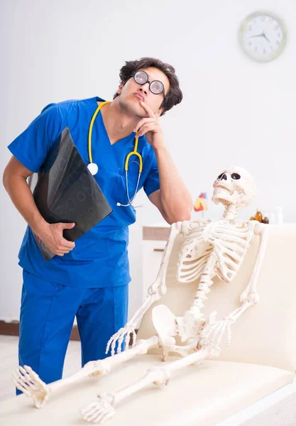 Doutor engraçado com esqueleto no hospital — Fotografia de Stock