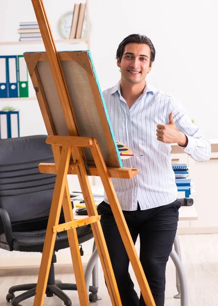 Jovem e bonito funcionário desfrutando de pintura no escritório — Fotografia de Stock