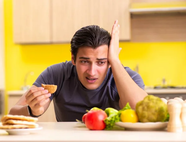 Hombre que tiene difícil elección entre la comida sana y no saludable — Foto de Stock