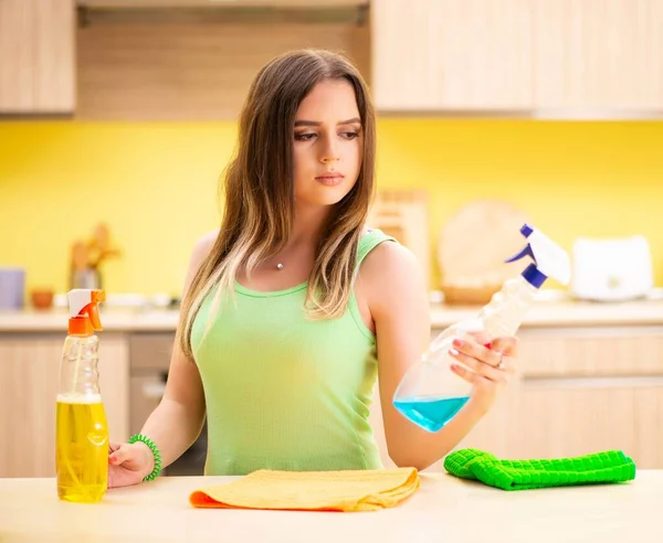 Молода блукаюча жінка полірує стіл на кухні — стокове фото