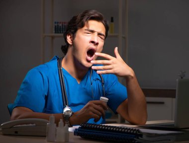 Hastanede gece vardiyasında çalışan yakışıklı genç bir doktor.