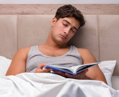 Adam yatakta kitap okumak