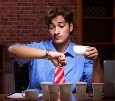 Kahve içen genç bir çalışan gece vardiyasında çalışıyor.